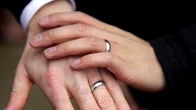 Silver rings on the hands of two gay men after getting married