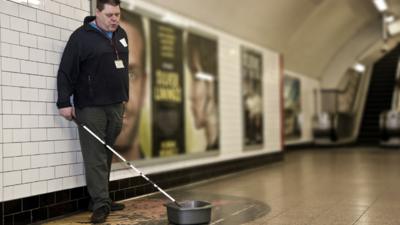 Mark busking with his cane and washing-up bowl