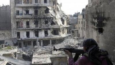 A Free Syrian Army fighter is in position in front of destroyed buildings in Aleppo, Syria on 29 November