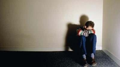 Man sitting the corner of a room