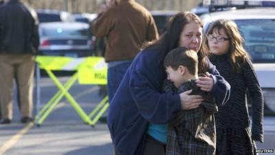 A young boy is comforted outside Sandy Hook Elementary School after a shooting in Newtown, Connecticut