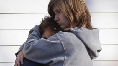 A couple embrace outside Sandy Hook school in Newtown, Connecticut