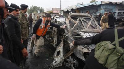 A damaged car in a bomb attack at Fauji Market in Peshawar