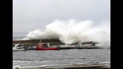 Waves crash over a harbour wall