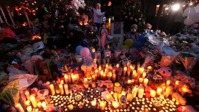 Candles are lit at a memorial for the shooting victims