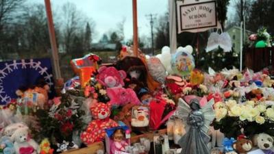 Flowers and tributes are placed in front of Sandy Hook School