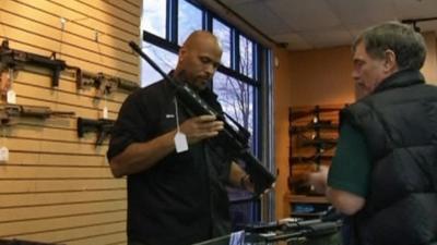 Gun store salesman showing customer an AR 15-style rifle