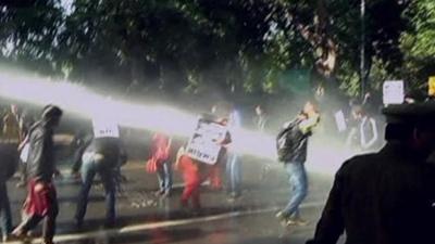 Protesters carrying placards being hosed by Delhi police