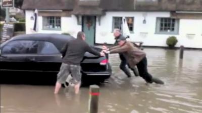 Men push car out of floodwater in Elsworth, Cambridgeshire