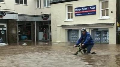 Man riding bicycle through wheel-deep flood water