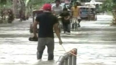 People carrying belongings through flooded road