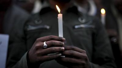 A man holds a candle in a vigil for the rape victim