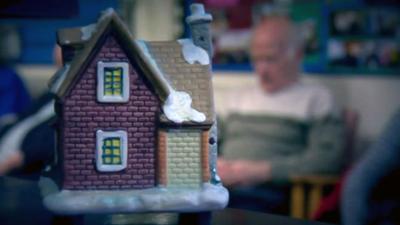 Model of snow-covered house with old man in background
