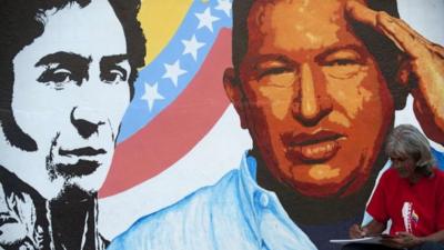 An artist draws next to a painting of Venezuelan President Hugo Chavez in Caracas, on 3 January 2013