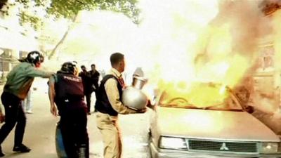 A man puts out a car that is on fire in Dhaka, Bangladesh