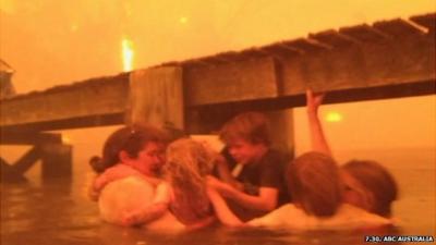 The Holmes family take refuge from the flames under a jetty