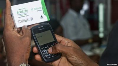 A texter typing in a number from a medicine packet into his mobile phone in order to check the authenticity of the drug