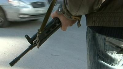 Man in jeans and jacket holding rifle