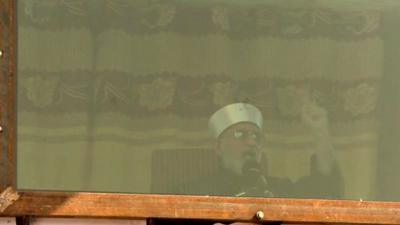 Tahir-Ul-Qadri speaking from behind bulletproof glass