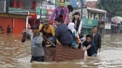 People being transported across a flooded road on a wooden cart in Jakarta