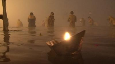 People and candle in water at Sangam