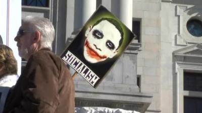 Protester hold sign showing Obama as 'the joker'