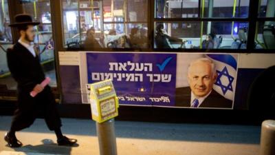 People walk past Netanyahu poster