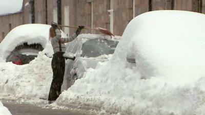 Woman scraping snow from car