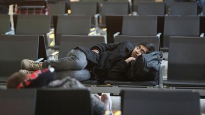 A man asleep on chairs at Terminal 5