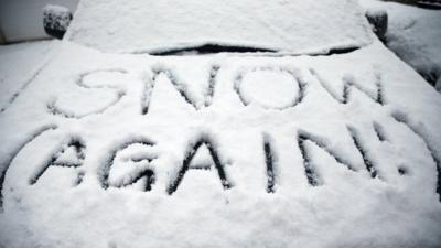 'Snow again' written on a car bonnet covered in the white stuff.