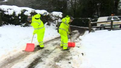 Workers clearing snow on a driveway