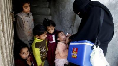 Pakistani health worker administering polio medication