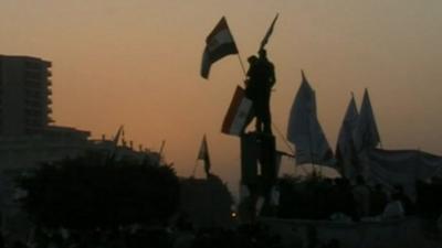Silhouettes of protesters with flags in Tahrir Square