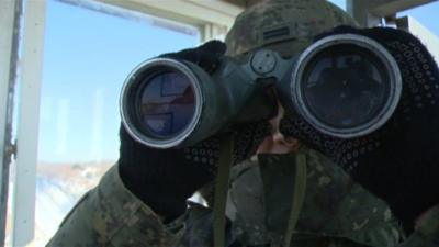 A soldier looks through binoculars