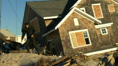 The BBC's Jon Sopel walks away from a house damaged by Sandy