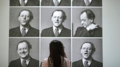 A worker poses next to photographs of Kurt Schwitters