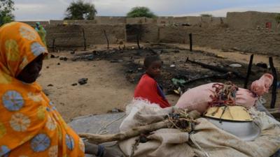 Woman and child next to destroyed house