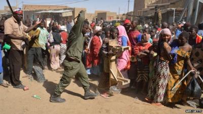 A Malian soldiers tries to disperse the crowd on January 29, 2013 in Timbuktu as residents plunder stores they say belong to Arabs, Mauritanians and Algerians