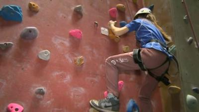 School pupil climbing a climbing wall