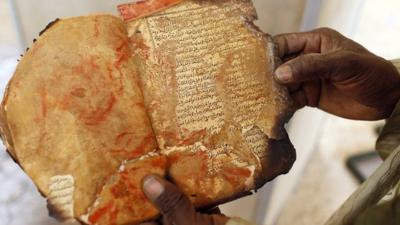 A museum guard displays a burnt ancient manuscript at the Ahmed Baba Institute in Timbuktu on 31 January 2013