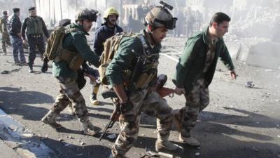 A wounded person is carried by soldiers at the site of a suicide bomb attack in Kirkuk