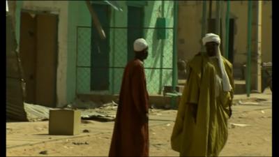 Two men outside looted building