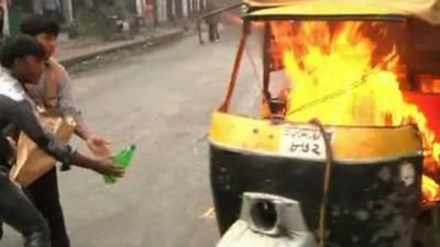 Protesters putting a tuk tuk on fire