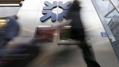 A pedestrian walks past a branch of the Royal Bank of Scotland in the City of London