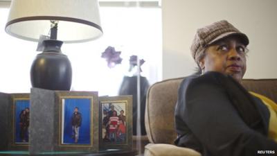 Shirley Chambers sitting by photos of her children in her home