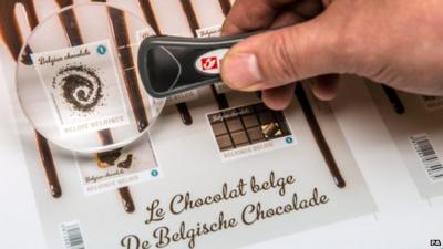 A Bpost worker uses a magnifier to check the quality of newly printed chocolate stamps at the Bpost