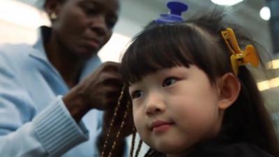 Chinese girl has her hair braided in Beijing