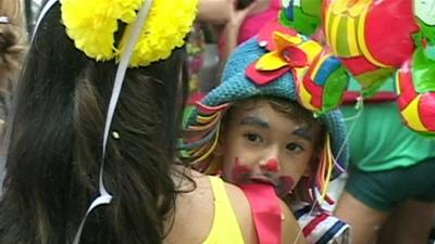 A child in a colourful costume and clown-like make up takes part in the carnival