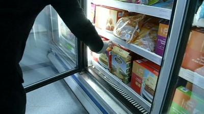 Person reaching for frozen food packet in supermarket