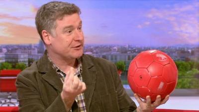 Jodrell Bank's Tim O'Brien using a football to explain the scale of the asteroid compared to Earth